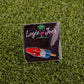 The Red White Blue Popsicle by Ballmarkers by Logie Joe’s is a novelty golf pin that doubles as a premium ball marker, shaped like a rocket pop and displayed on black packaging with artificial green grass.