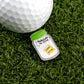 A white golf ball rests on grass beside Ballmarkers by Logie Joe’s Jar of “F”s, a funny ball marker shaped like a jar with a green lid and a single yellow block labeled “last fuck” inside.
