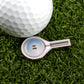 A golf ball on artificial grass next to Ballmarkers by Logie Joes Magnify Glass marker, which resembles a magnifying glass and features “Your Penis” in the center—a funny pick for fans of novelty golf accessories.